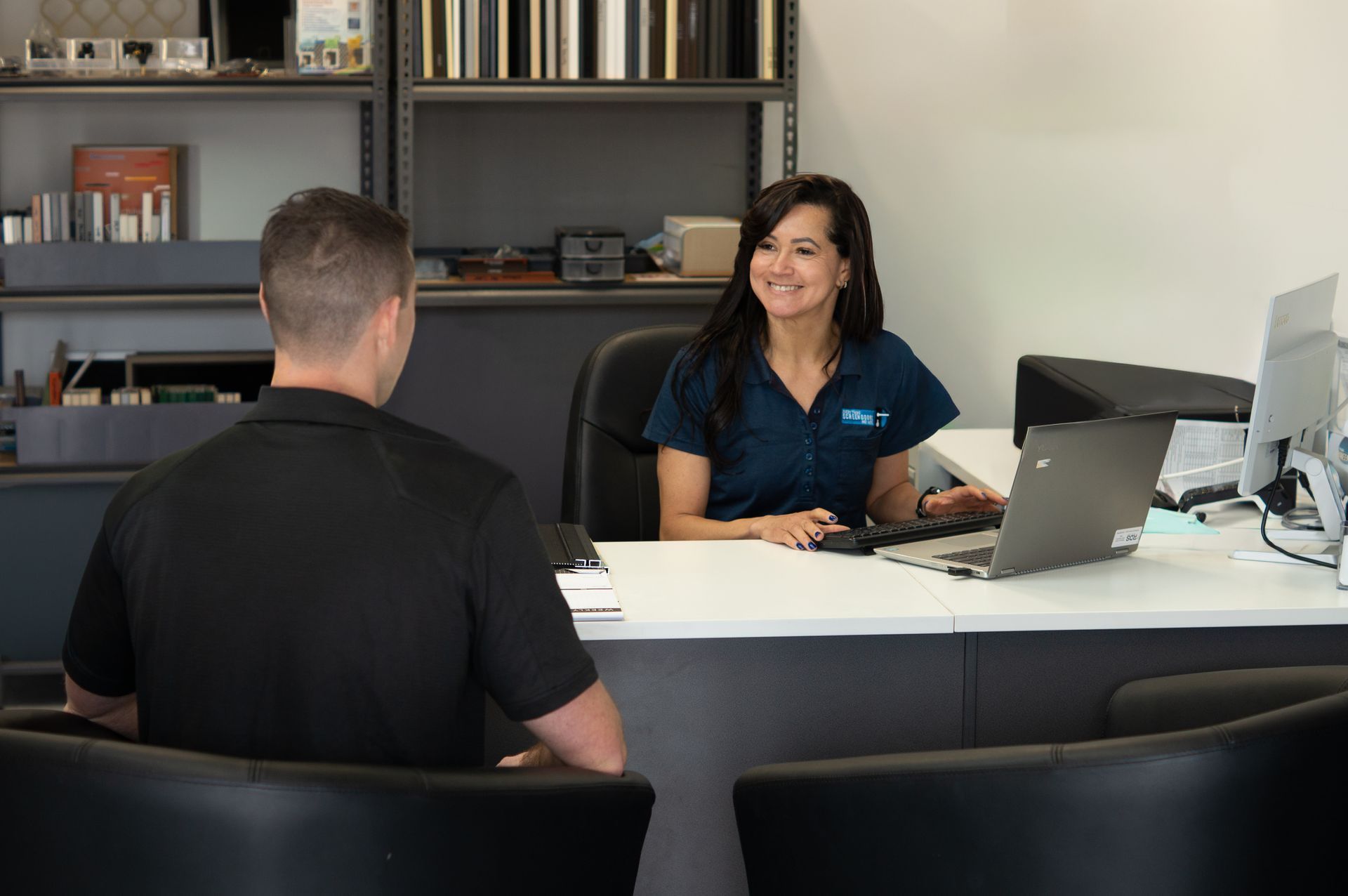 A Woman in Blue Scrubs Smiles, Talking to a Man in a Black Shirt — Everything Screendoors & More In Wollongong, NSW