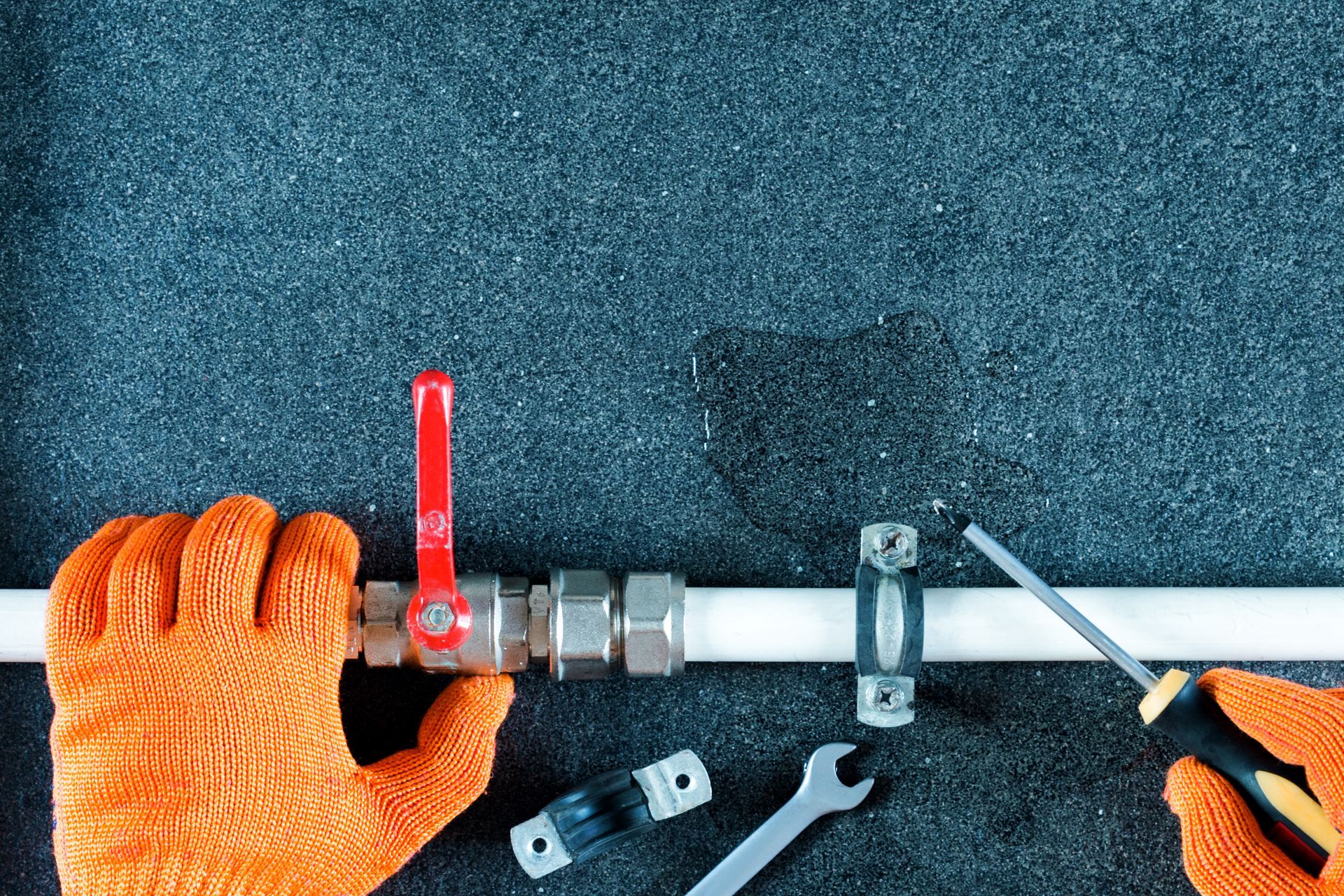 Plumber's Hands in Orange Gloves Working on a Pipe — JLH Plumbing, Gas & Roofing in Vincentia, NSW