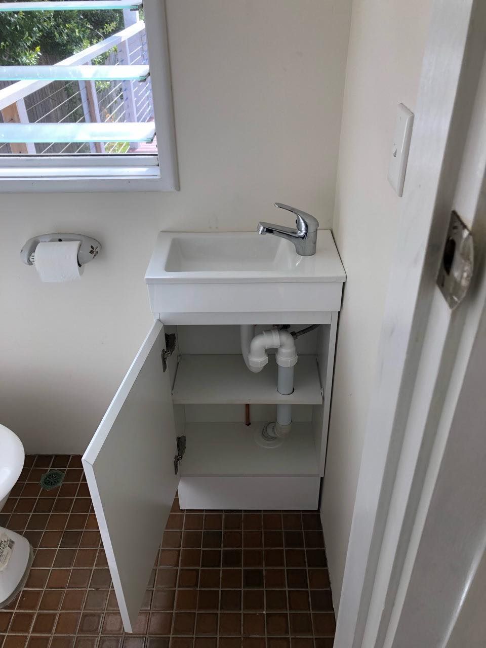 Small White Bathroom Cabinet With Sink and Open Door — JLH Plumbing, Gas & Roofing in South Nowra, NSW