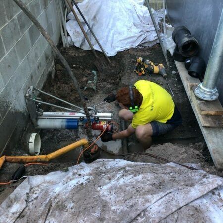 Person in Yellow Shirt Using a Core Drill — JLH Plumbing, Gas & Roofing in Kiama, NSW