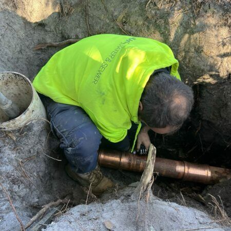 Plumber in Yellow Shirt Working on a Copper Pipe — JLH Plumbing, Gas & Roofing in Shellharbour, NSW