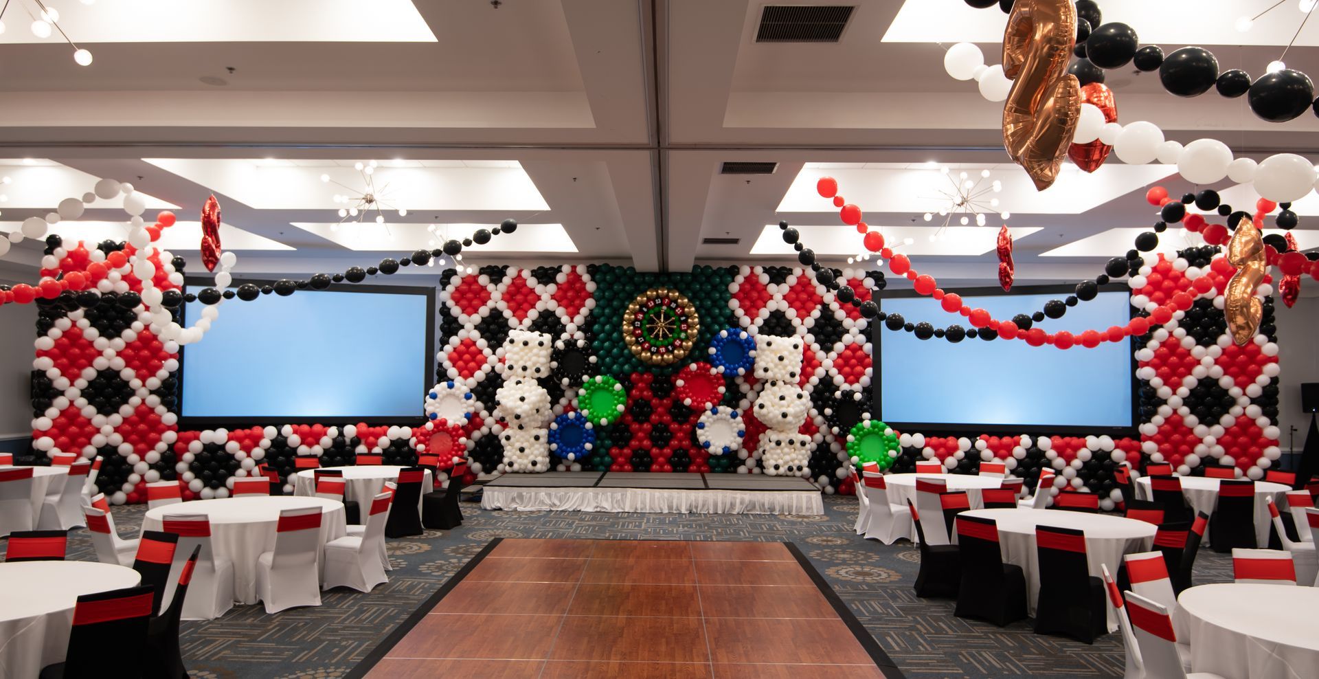 A large room filled with tables and chairs and balloons.