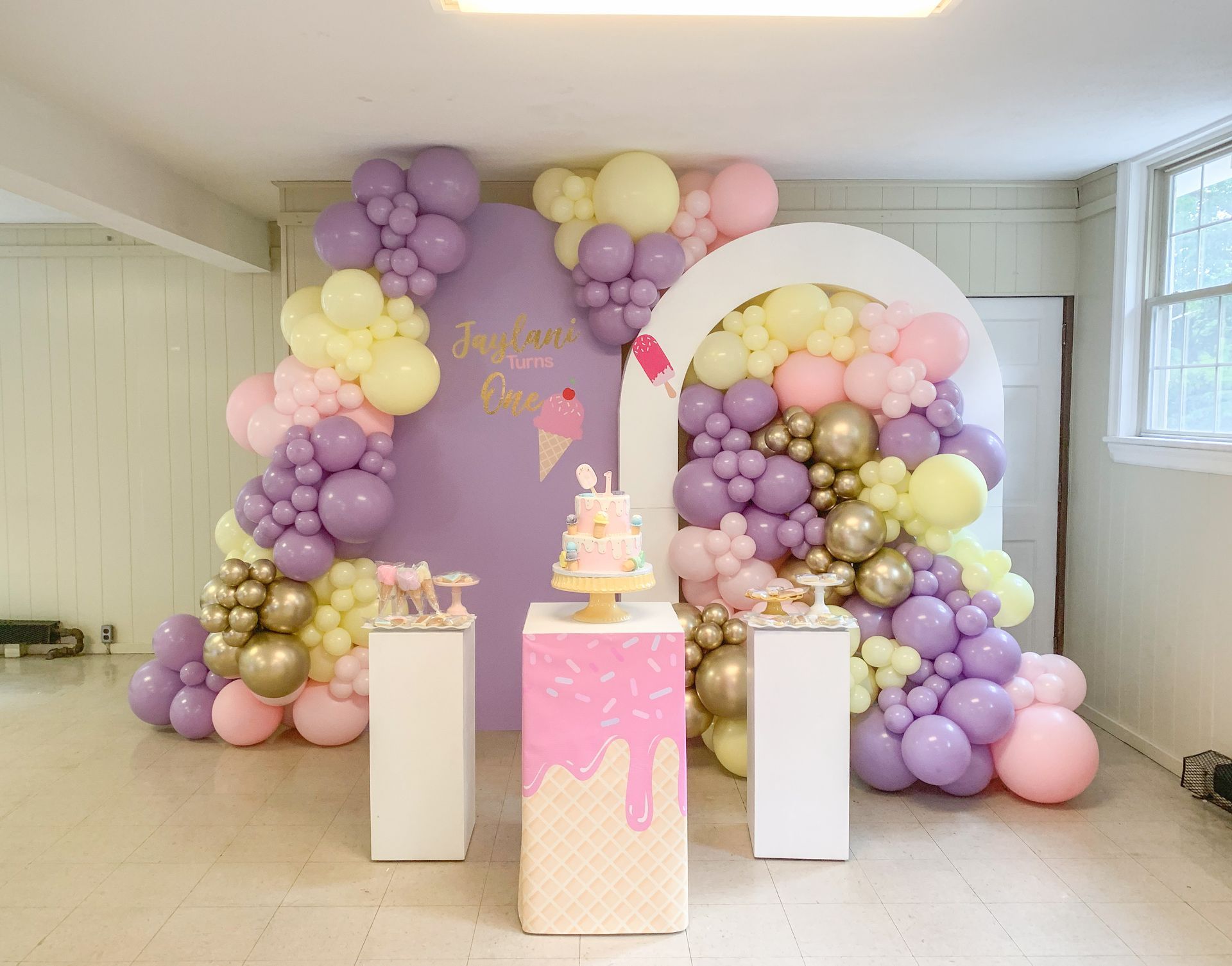 A room filled with balloons and a cake on a table.
