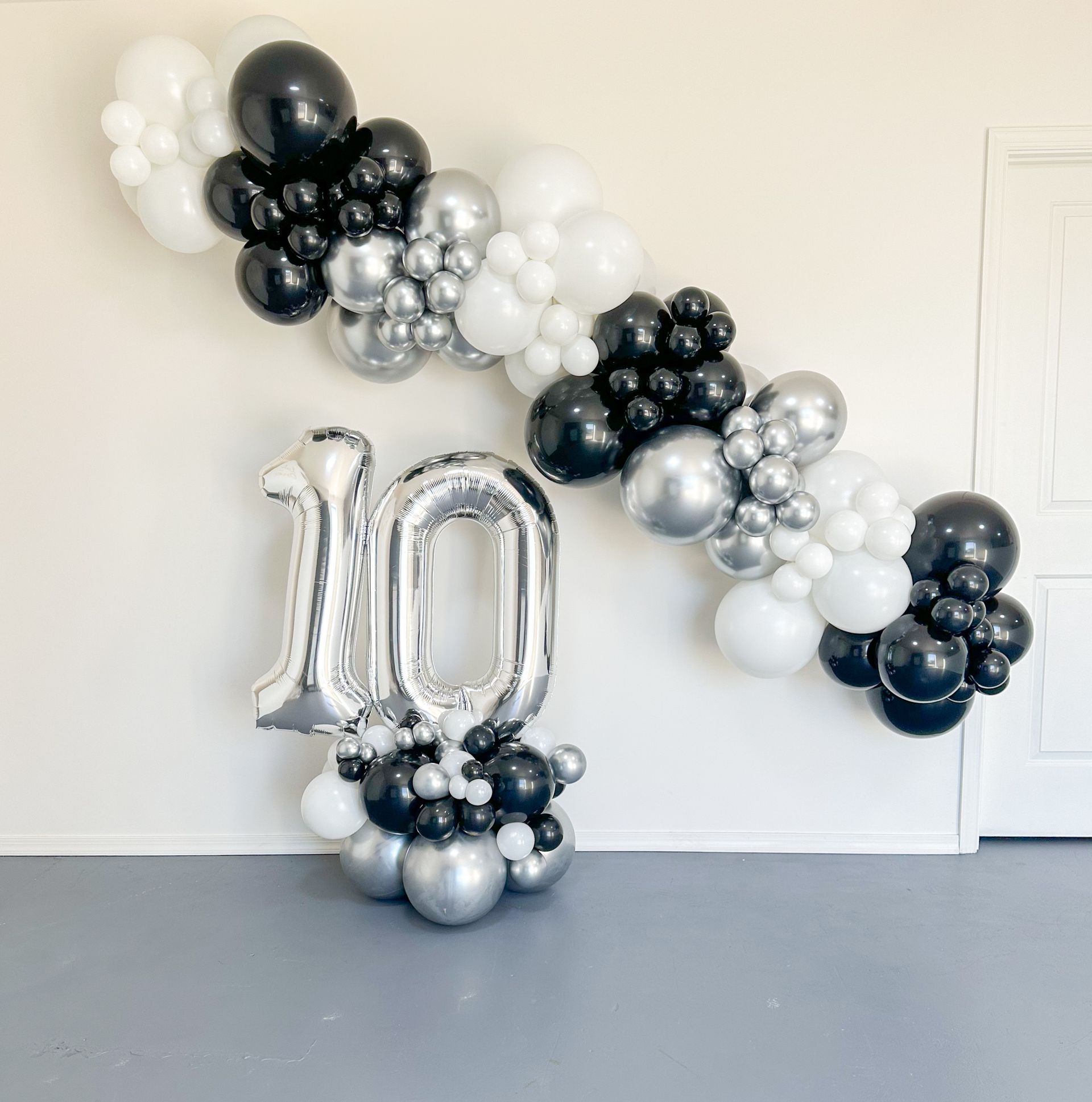 A couch is sitting in front of a wall with balloons hanging from it.