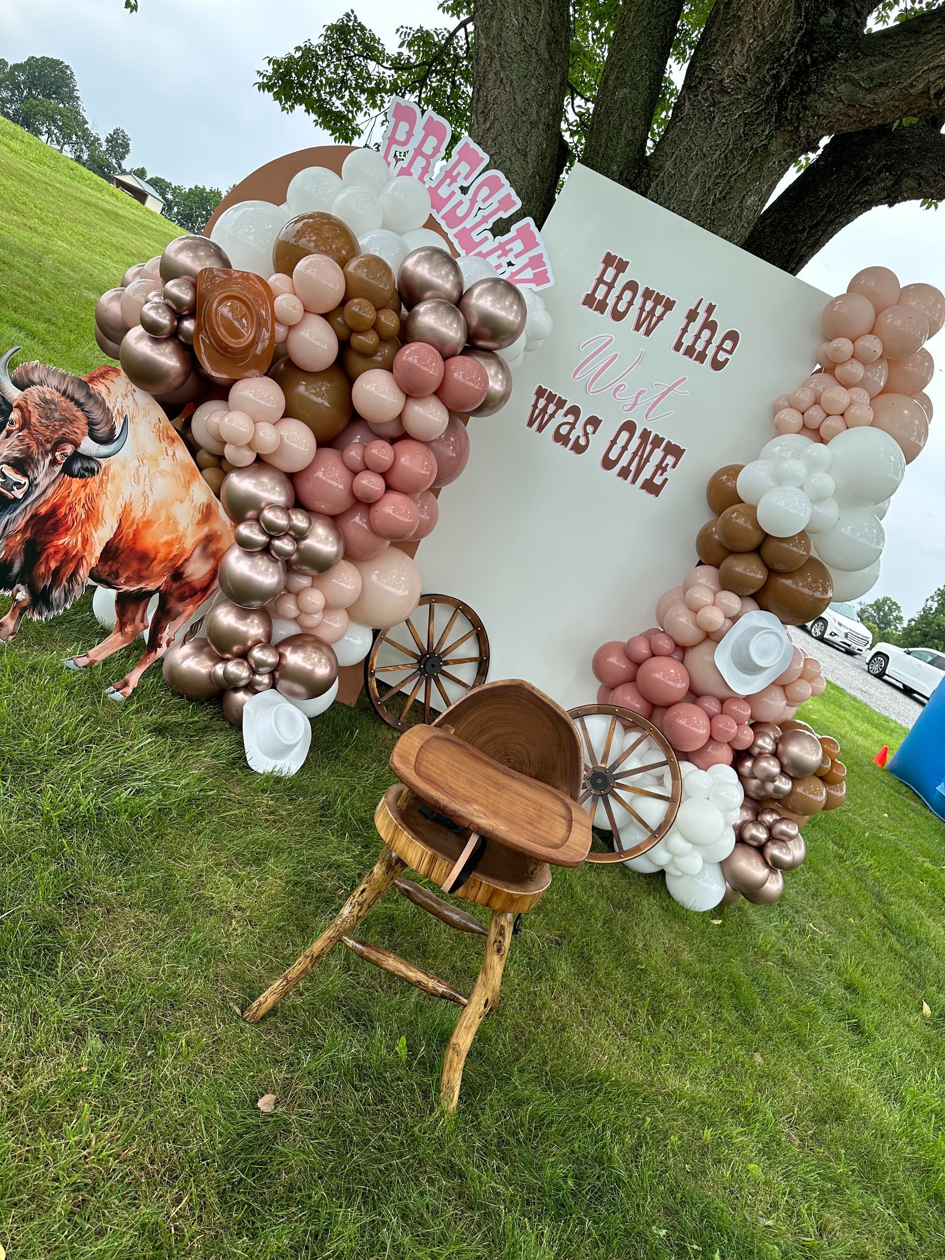 A baby chair is sitting in front of a wall filled with balloons.