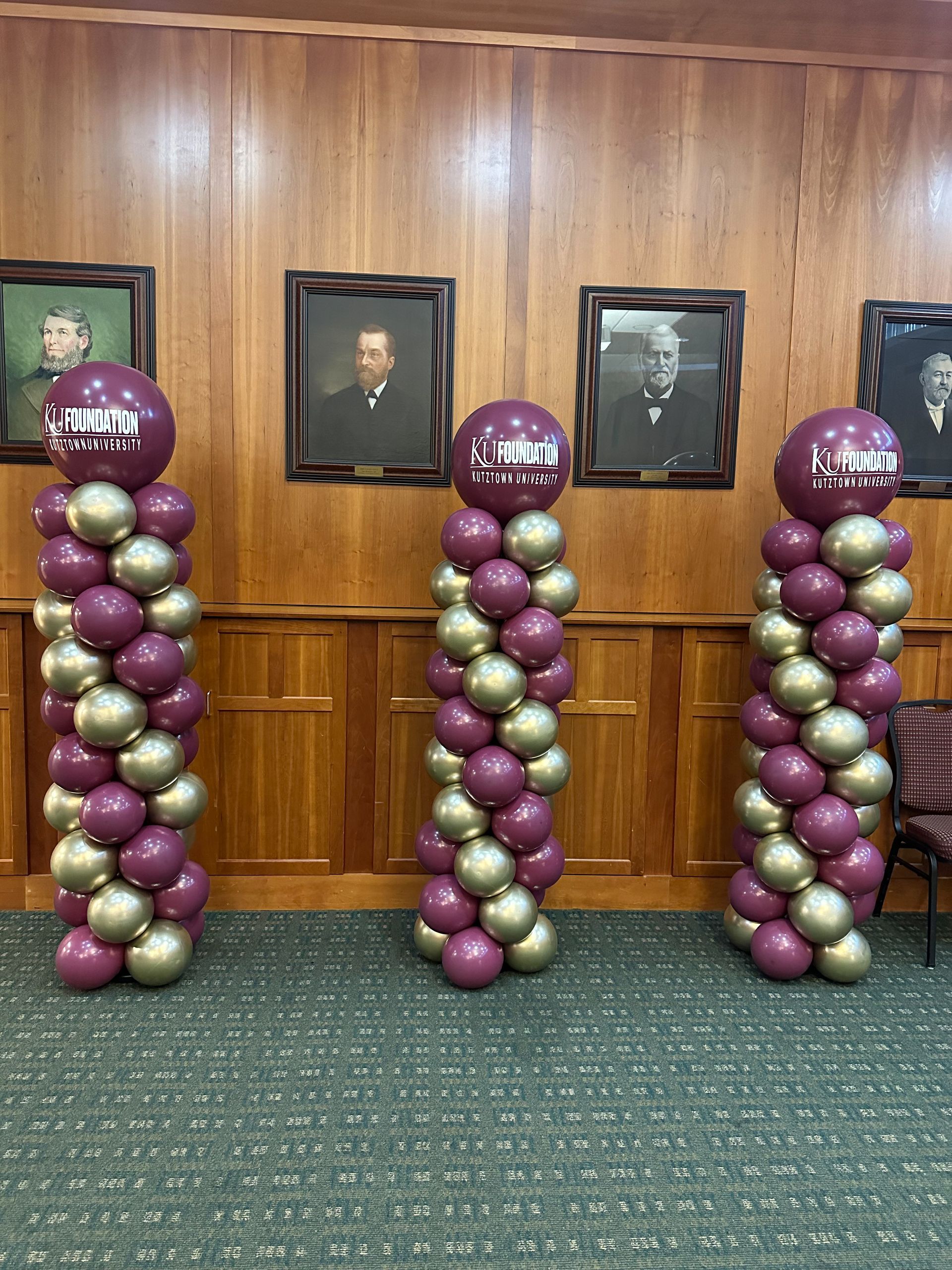 Three columns of purple and gold balloons in a room