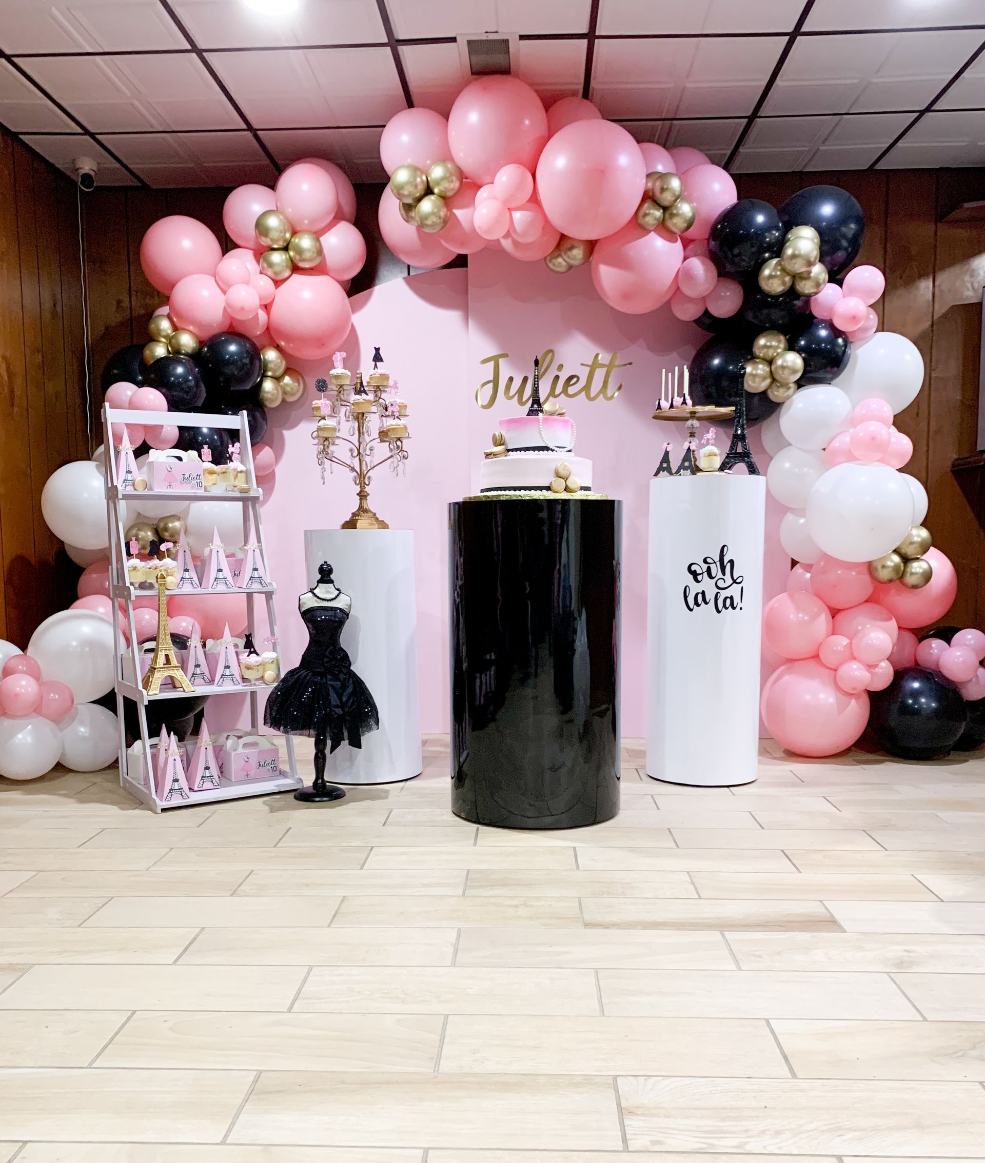 A room decorated with pink and black balloons and a cake.
