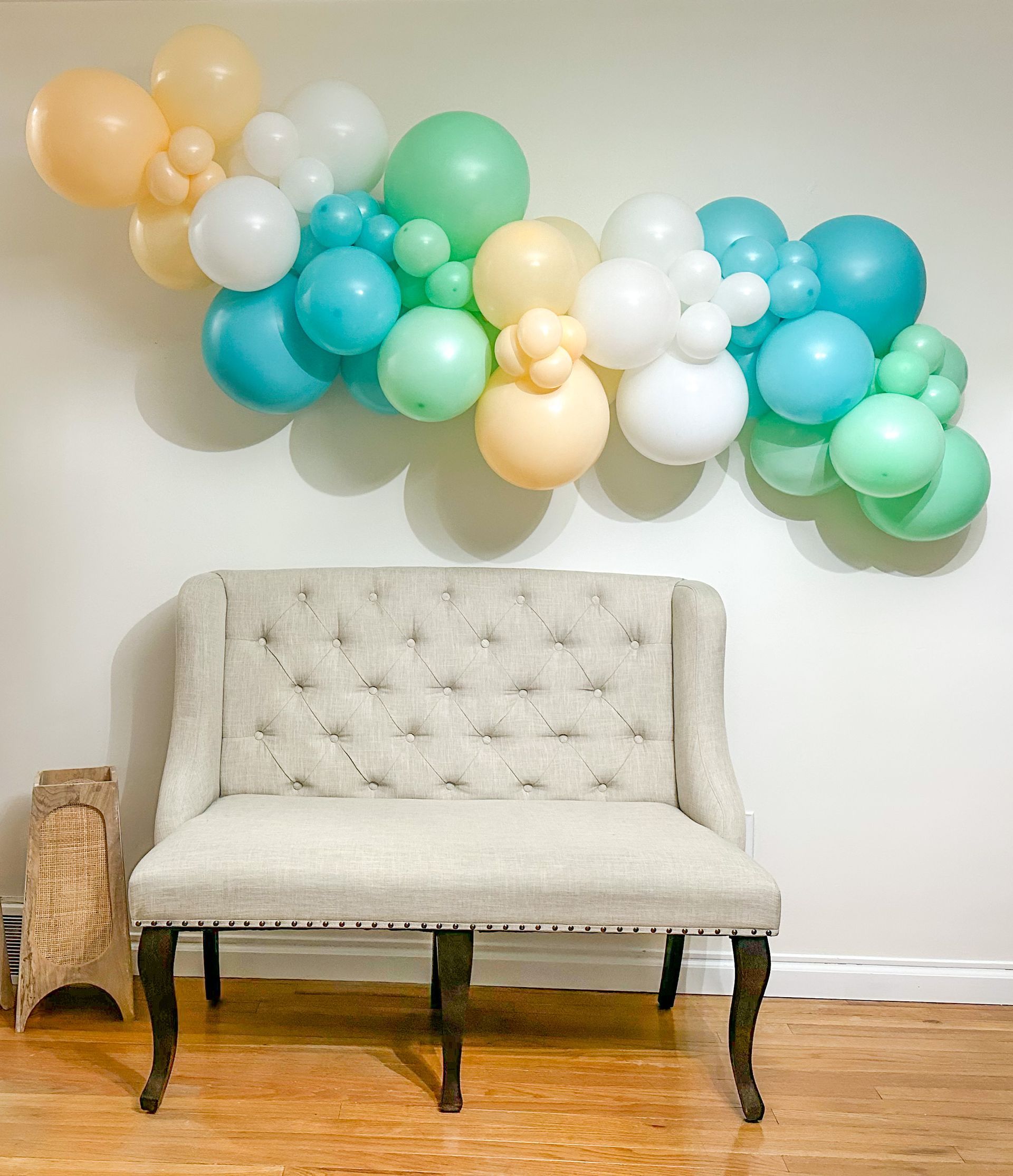 A couch is sitting in front of a wall with balloons hanging from it.