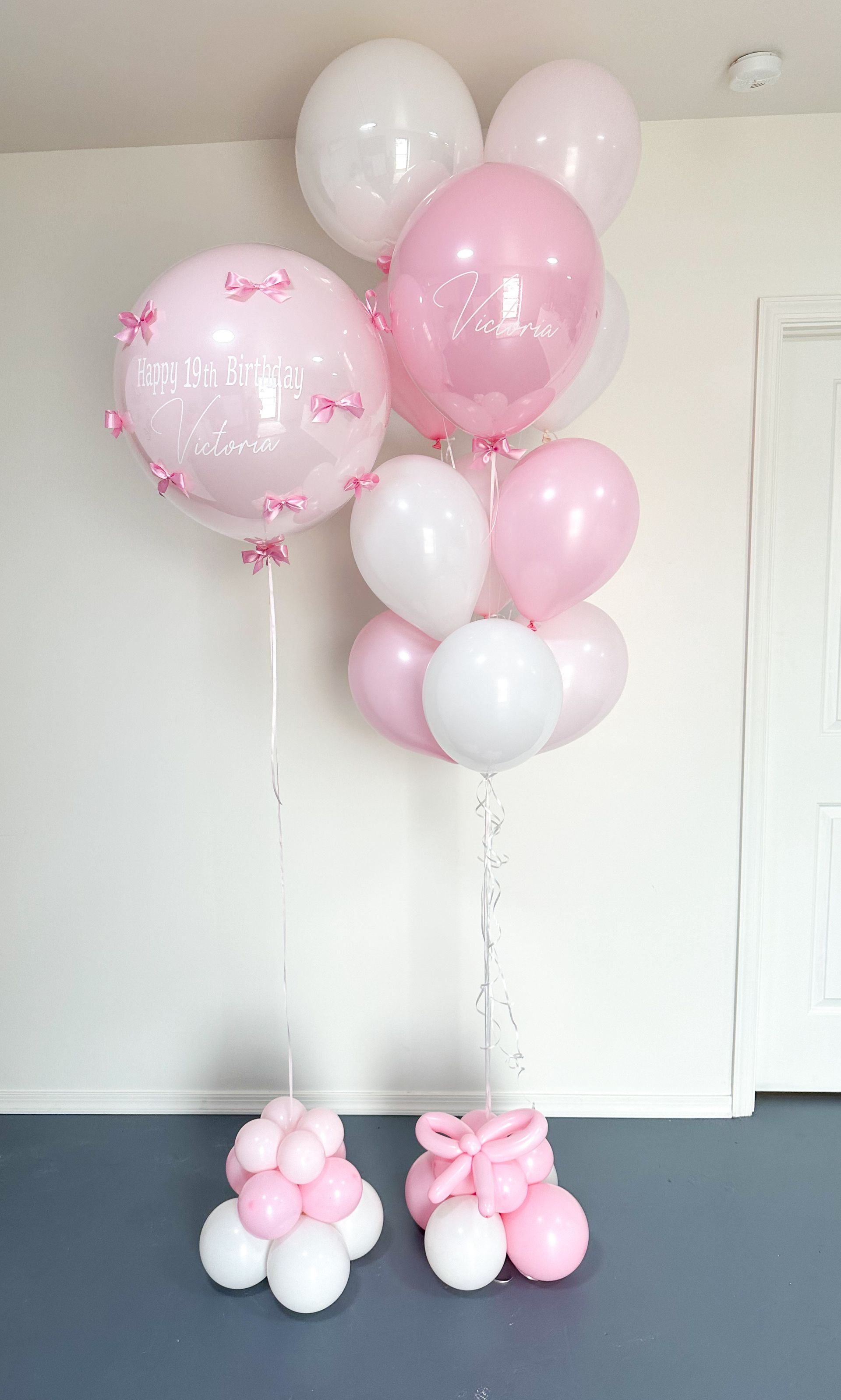 A  helium bunch of pink and white balloons sitting on top of a table.