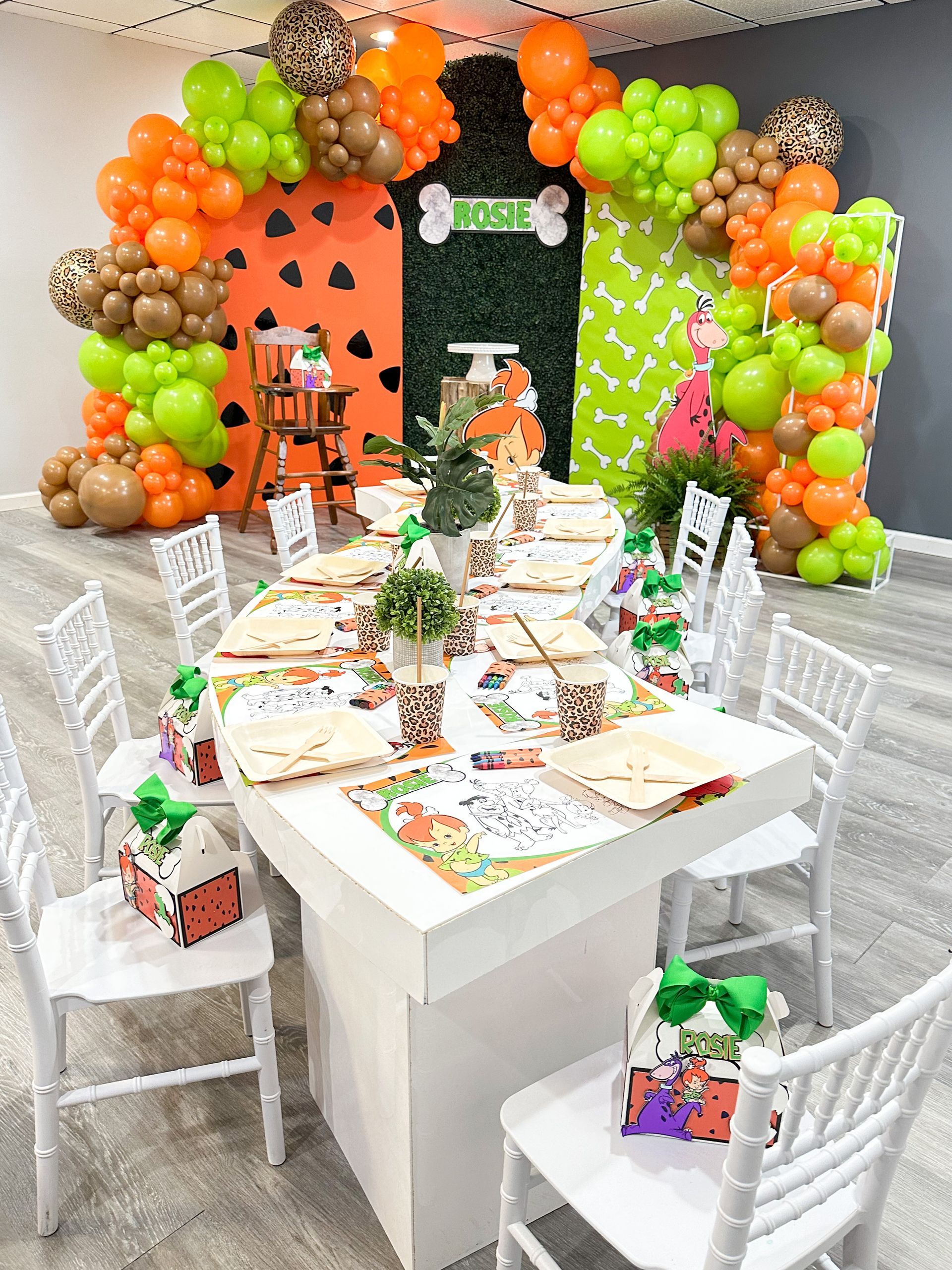 A table and chairs are decorated with balloons for a birthday party.