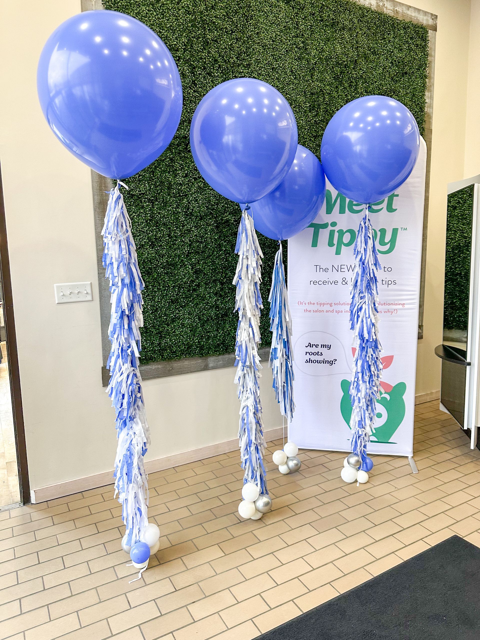 A bunch of purple balloons are sitting in front of a sign that says meet tippy