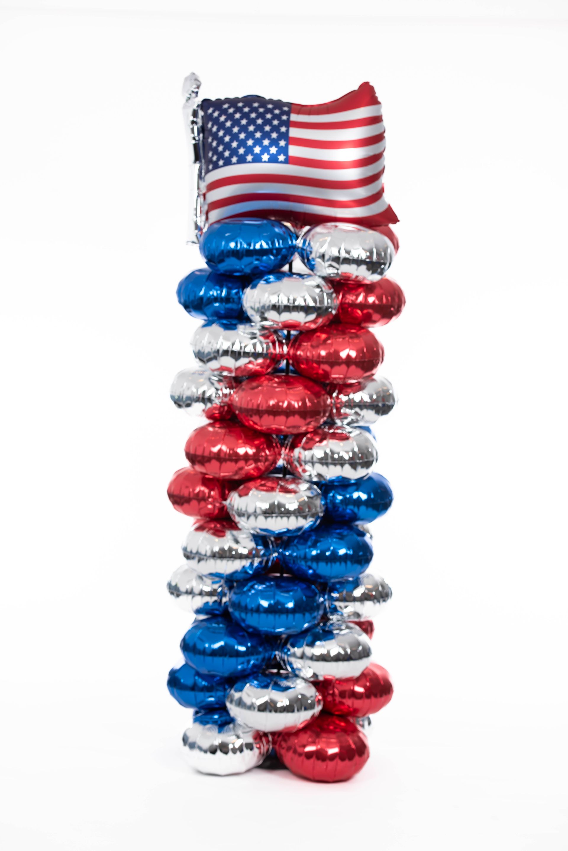 A stack of red , white and blue balloons with an american flag on top.