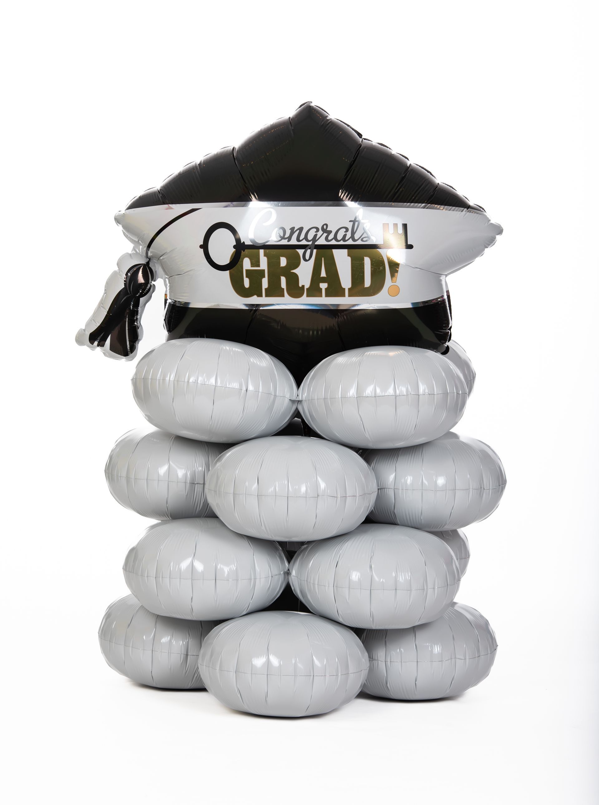 A stack of balloons with a graduation cap on top of them.