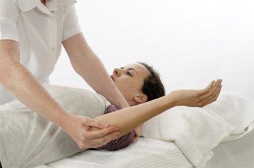 a female patient lying down and havin chiropractic treatment on her arm