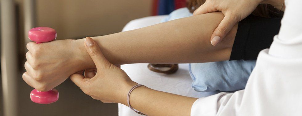 close up of a woman holding a small weight and having chirporactic treatment on her arm