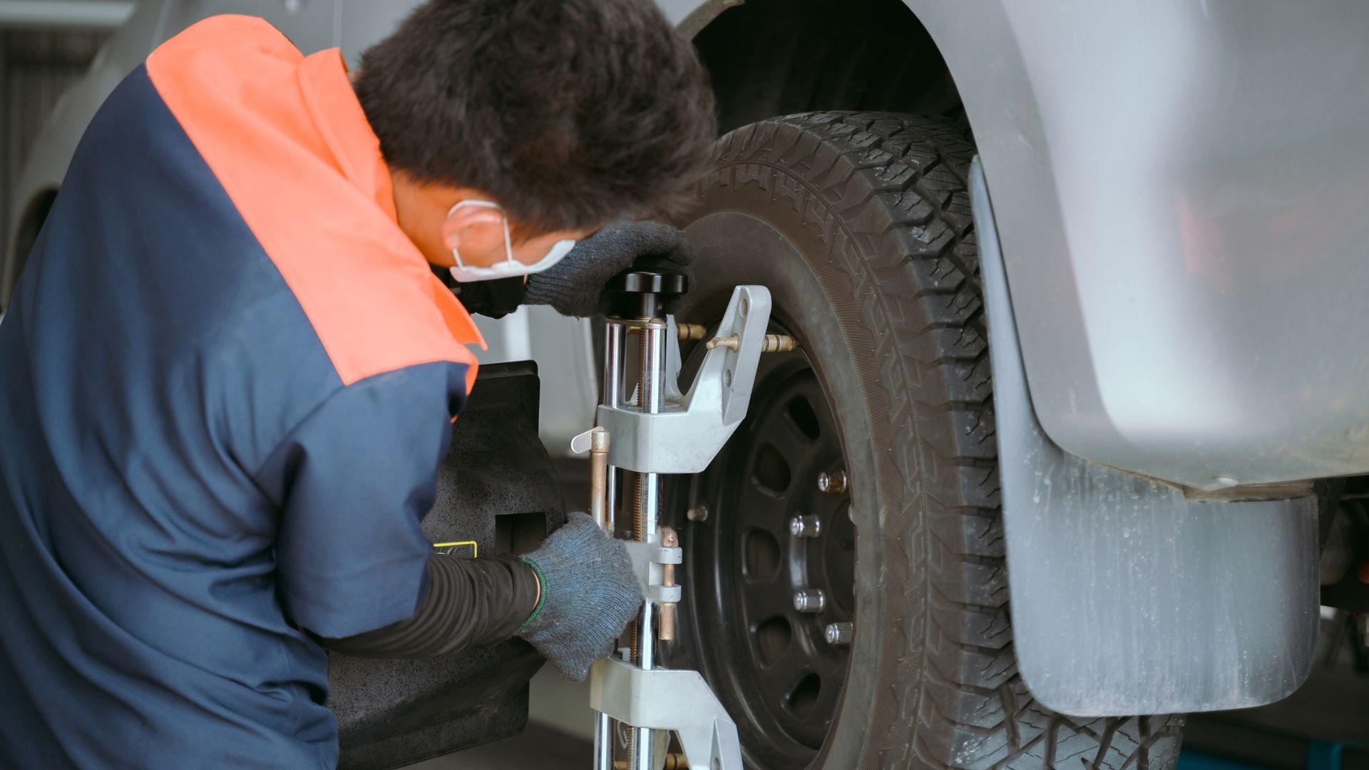 A man wearing a mask is working on a car wheel.