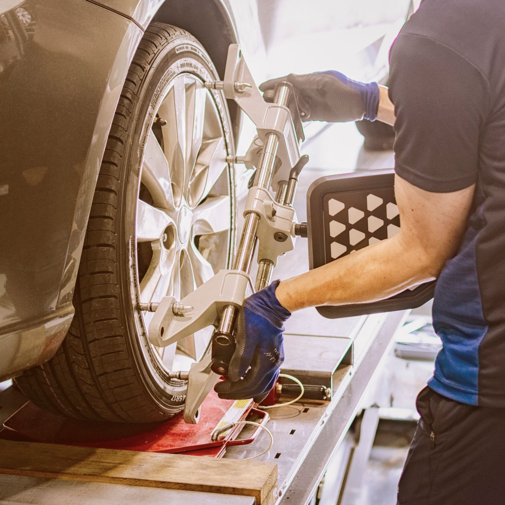 A man is working on a car wheel with a machine.