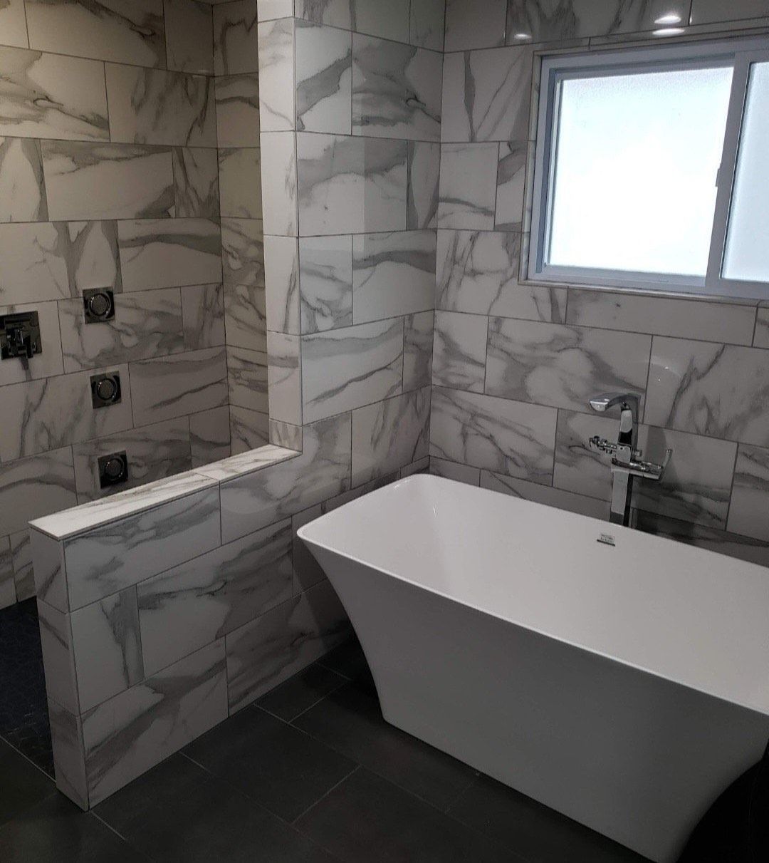A bathroom with a tub , shower , and window.