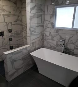 A bathroom with a tub , shower , and window.
