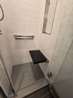 A bathroom with a walk in shower and a bench.