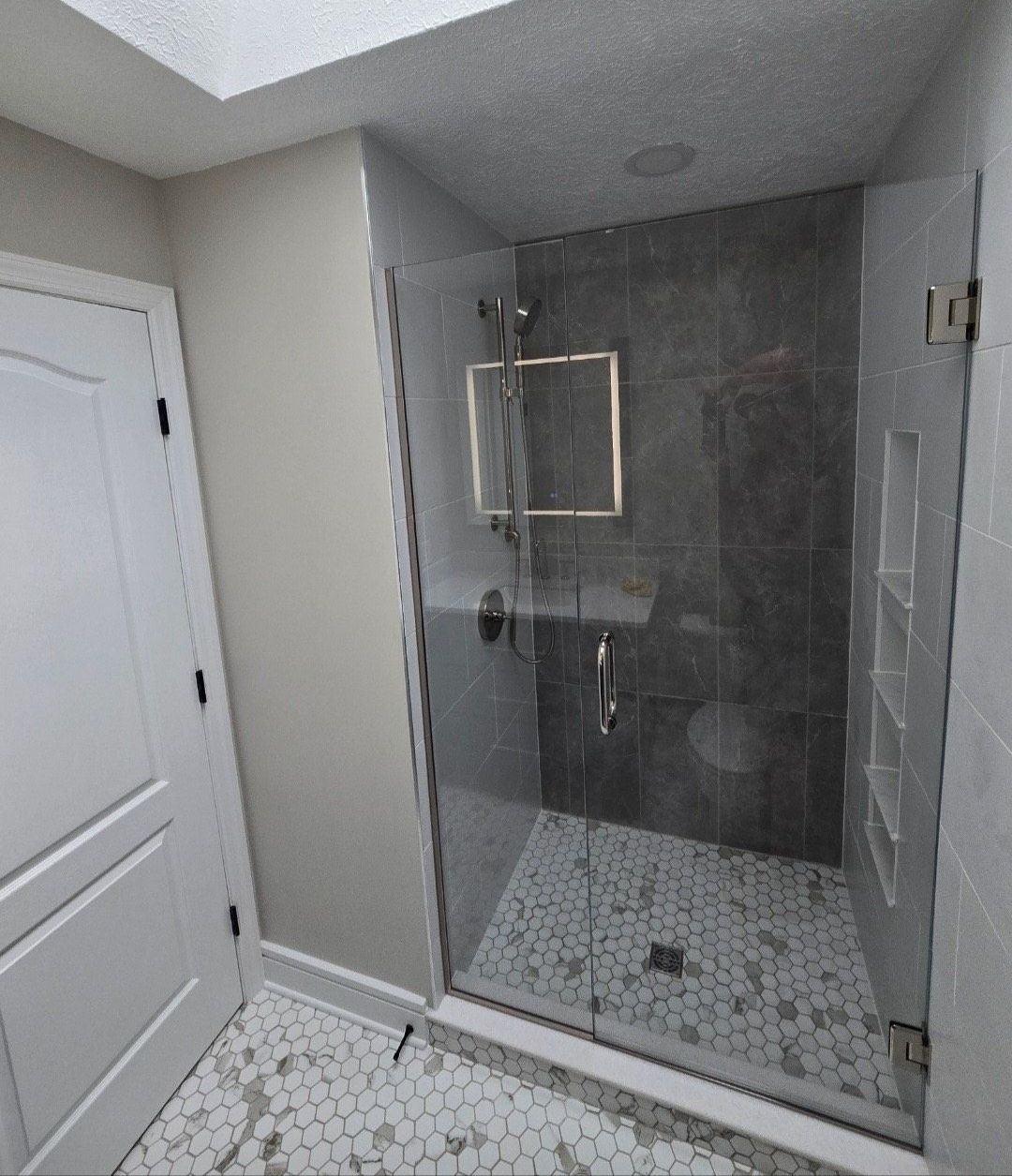 A bathroom with a walk in shower with a glass door