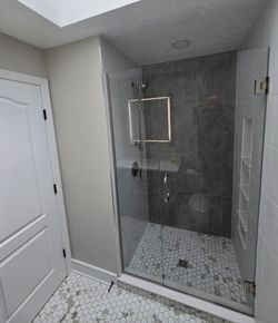 A bathroom with a walk in shower with a glass door