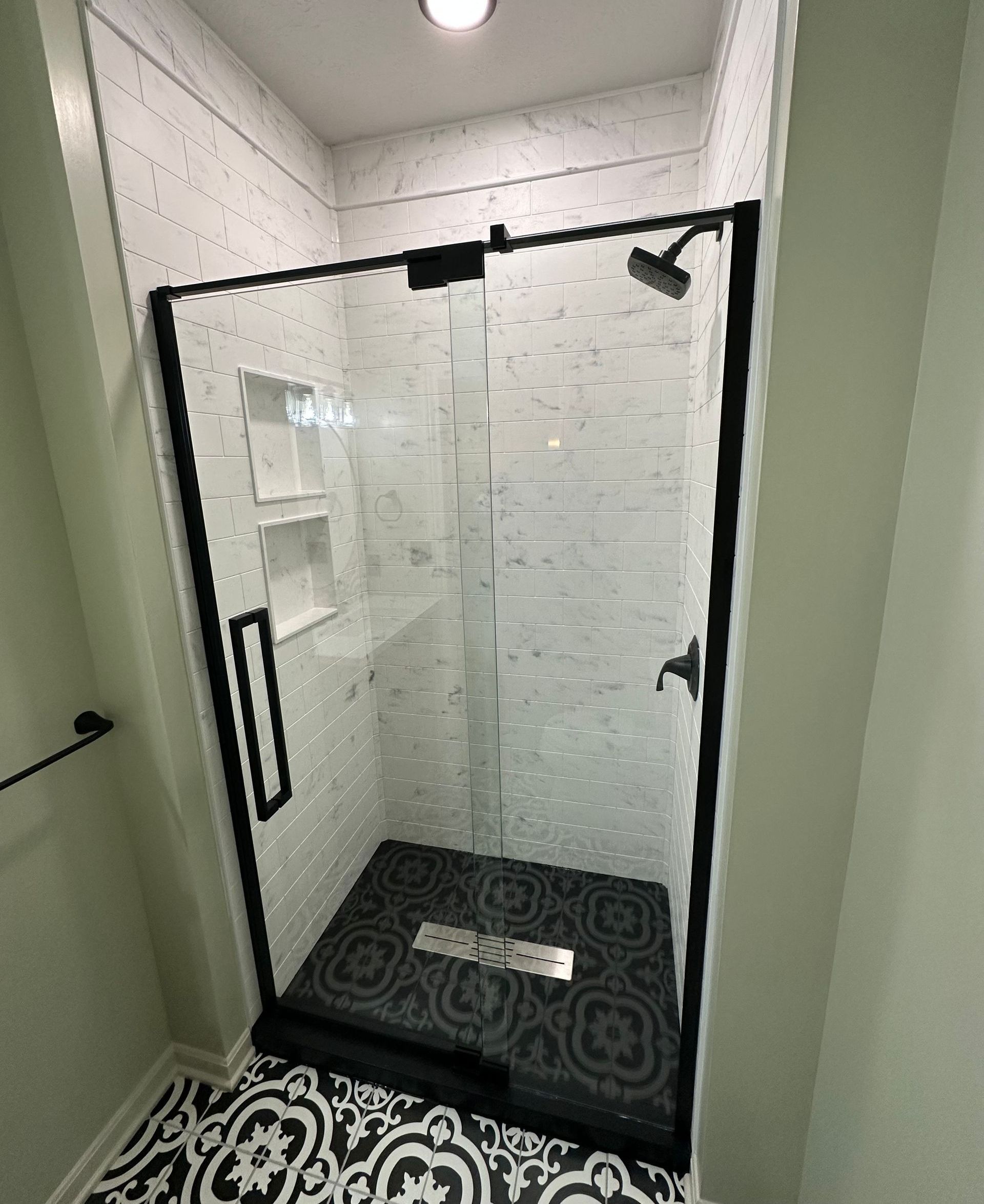 A bathroom with a walk in shower with a black frame.