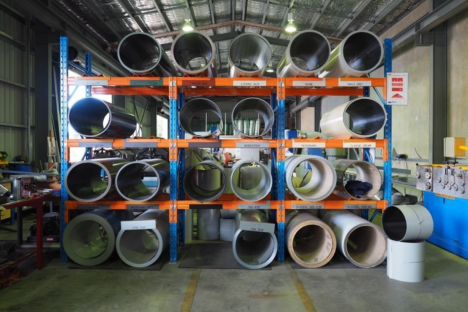 A Bunch Of Pipes Are Stacked On Shelves In A Warehouse — Fullerton's Plumbing Manufacture In Woree, QLD