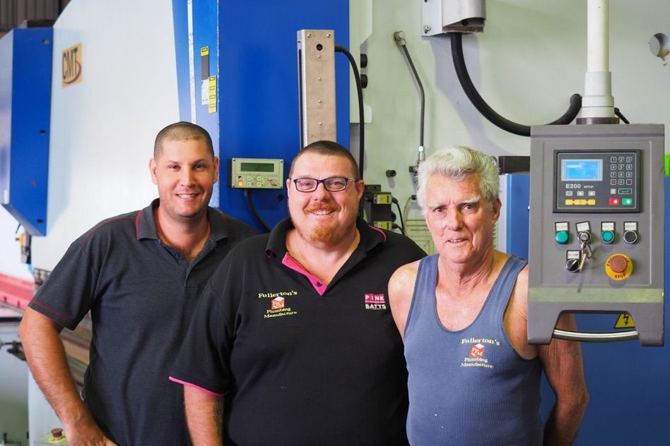 Three Men Are Posing For A Picture In Front Of A Machine — Fullerton's Plumbing Manufacture In Woree, QLD