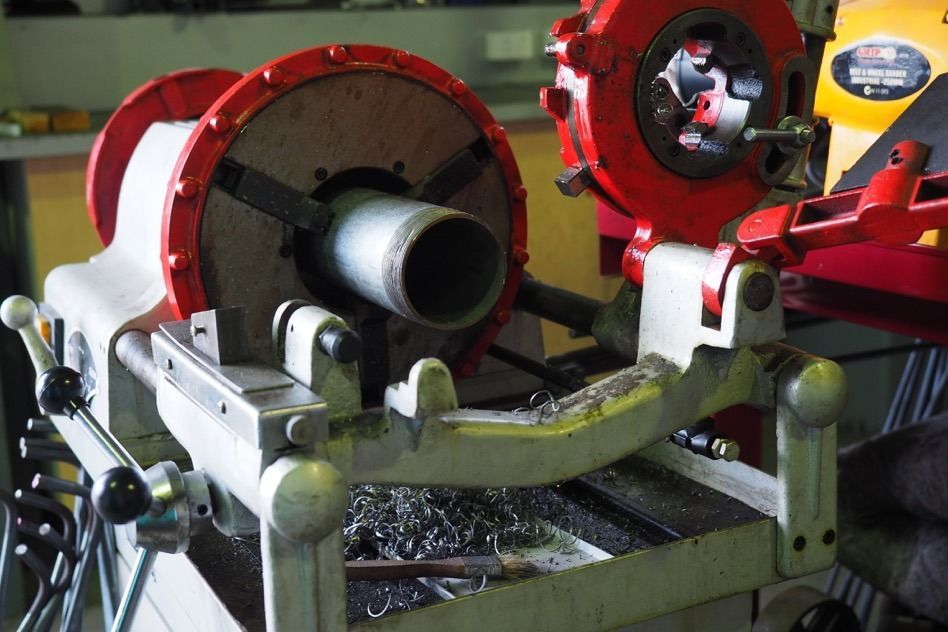 A Machine That Is Cutting A Pipe On A Table — Fullerton's Plumbing Manufacture In Woree, QLD
