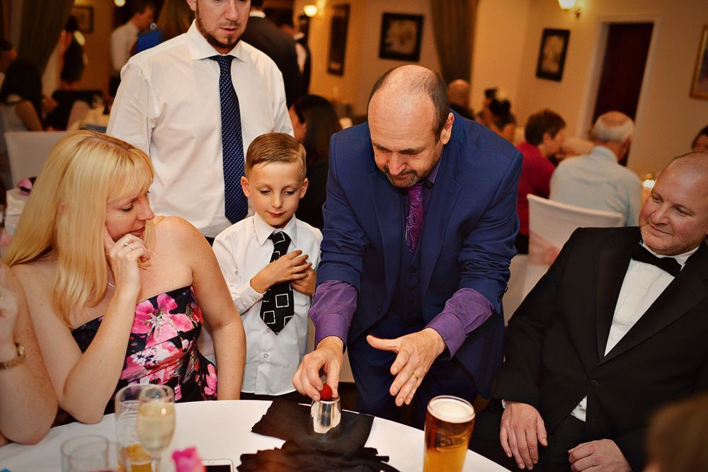 Paul Roberts, wedding magician, performs an interactive magic trick for delighted guests at a Liverpool wedding reception.