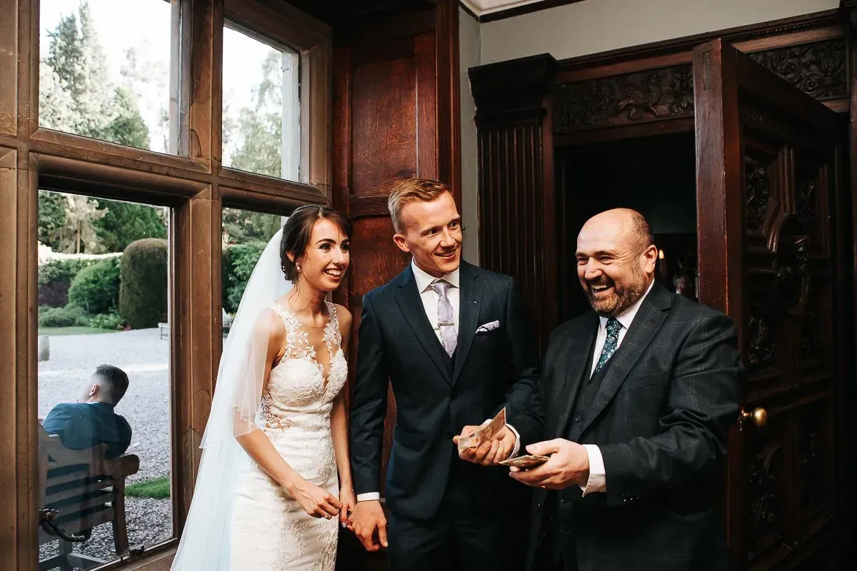 A bride and groom are posing for a picture with a man in a suit.