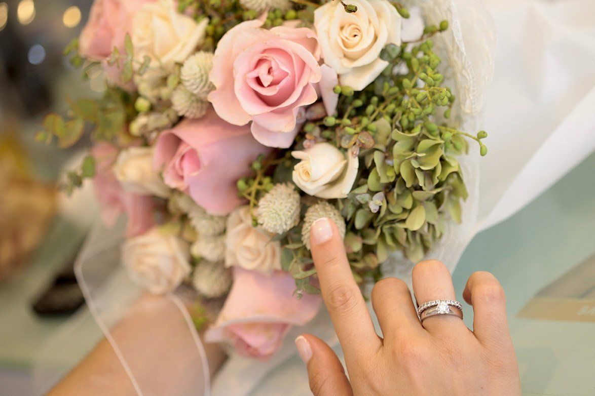 A woman is holding a bouquet of flowers and wearing a wedding ring.