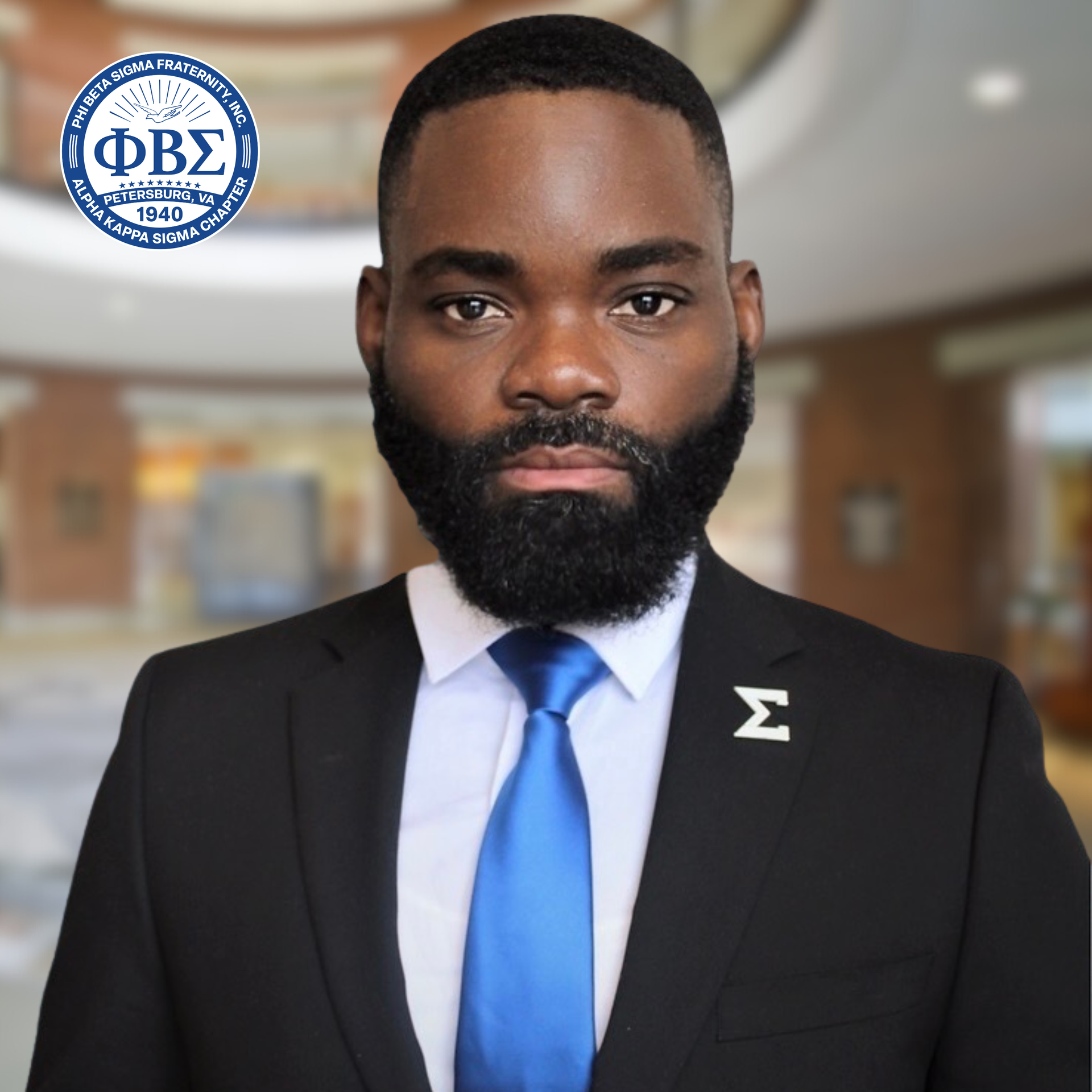President Jamal Briggs in a black suit and blue tie, Sigma insignia, serious expression, blurred indoor setting.