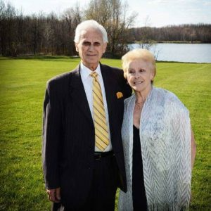 A man in a suit and tie is standing next to a woman in a white dress.
