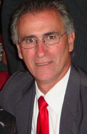 A man in a suit and tie is smiling for the camera