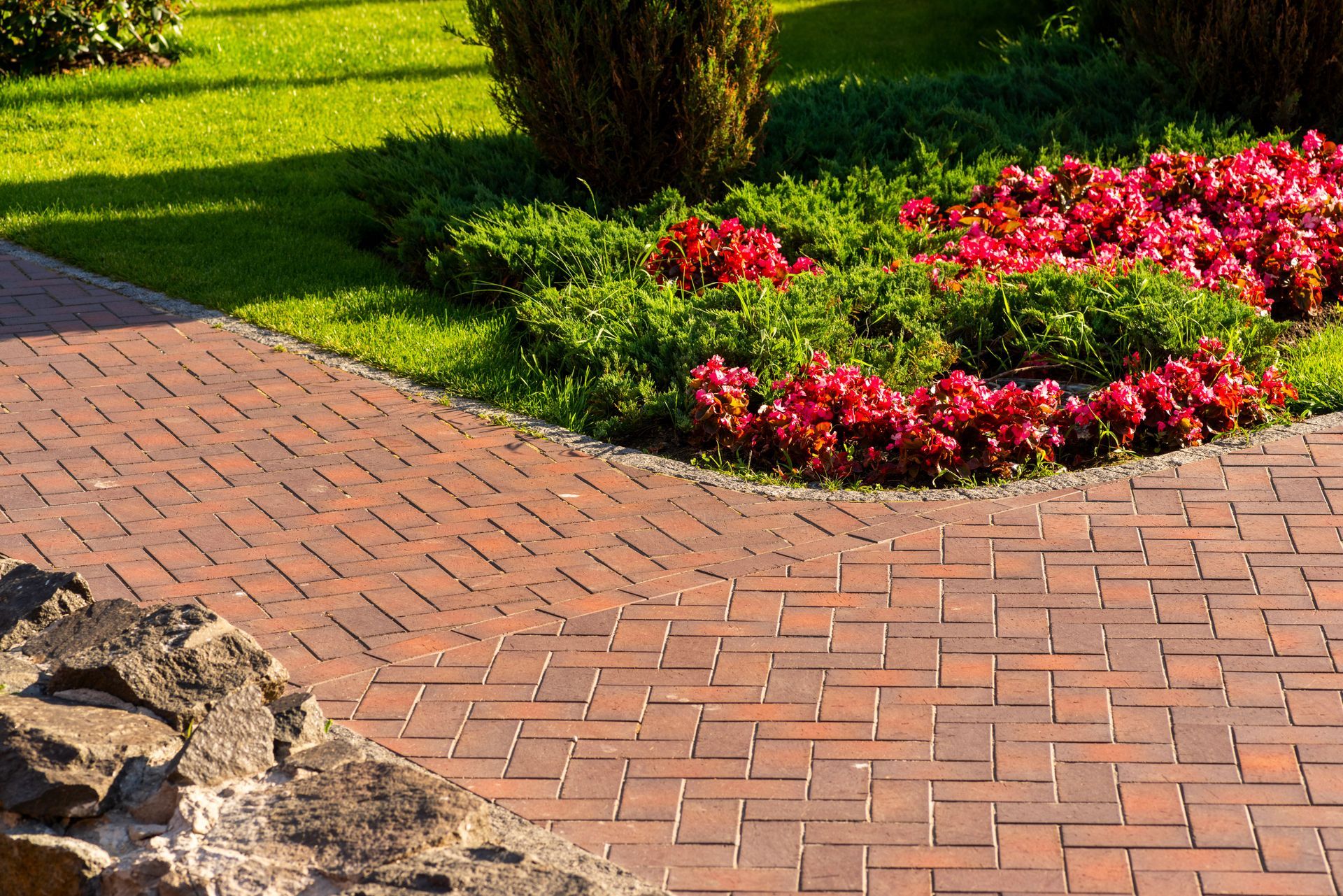 Red paving slab path winding through a garden with vibrant flowers in landscape design.