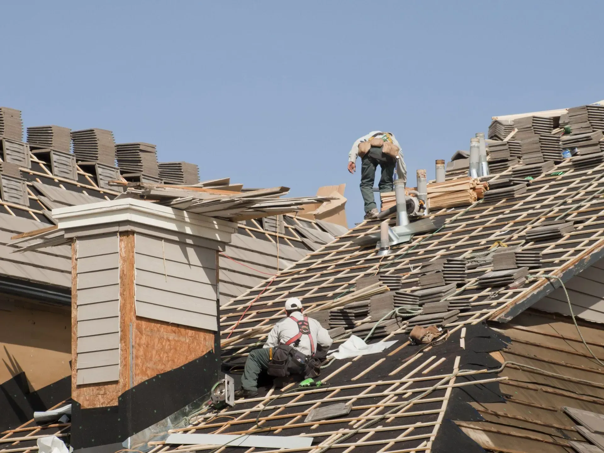 Two men are working on the roof of a building.