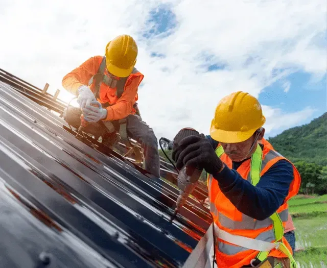 Two construction workers are working on a roof.