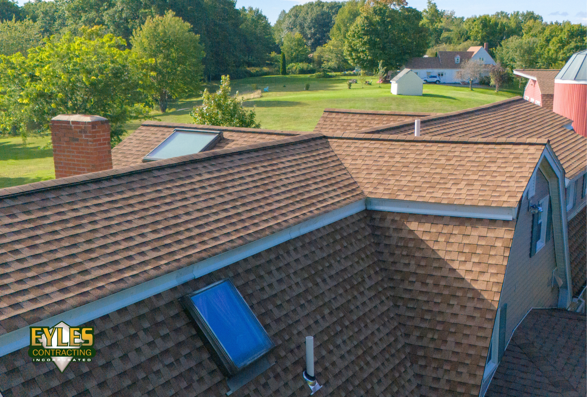 Residential home with an architectural shingle roof, chimney, and skylights.