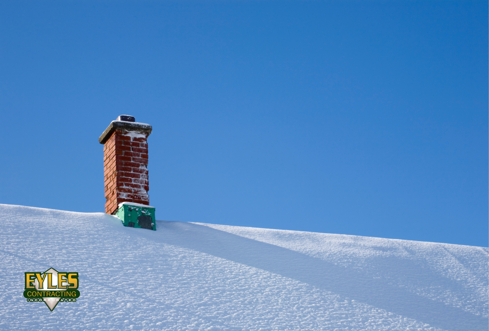 Snow-covered chimney and shingle roof on a residential home in winter.