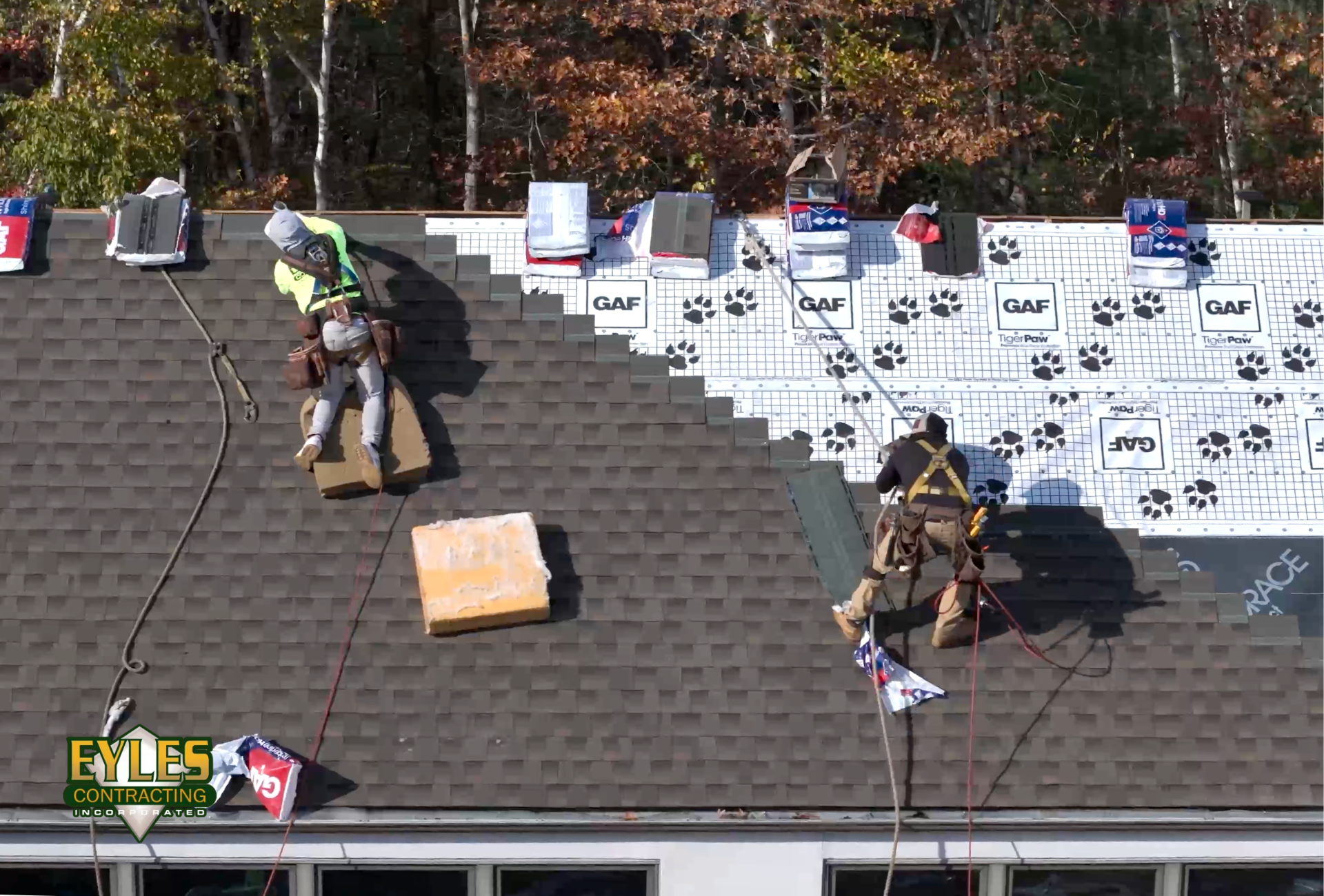 Roofing contractors installing architectural shingles during a roof replacement.