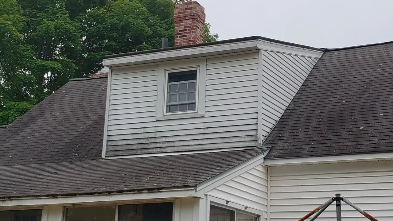 A white house with a brown roof and a chimney.