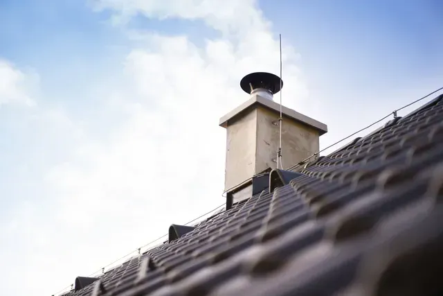 A chimney on top of a roof with a blue sky in the background.