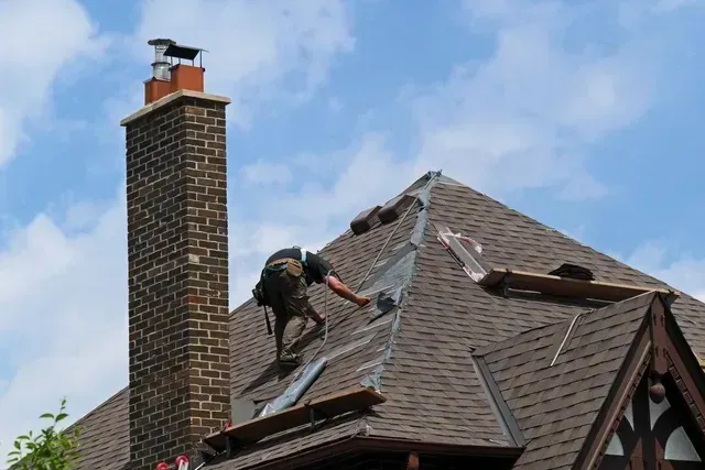 A man is working on the roof of a house.