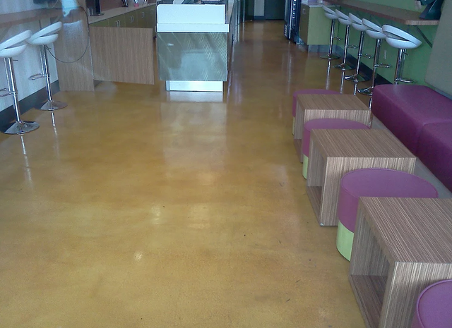 a restaurant with a concrete floor and purple ottomans