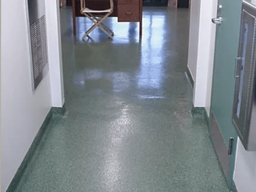 a hallway with a green floor and a desk in the background .