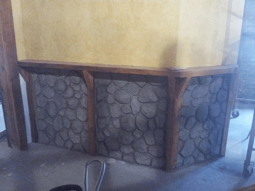 a stone wall with wooden beams and a chair in front of it