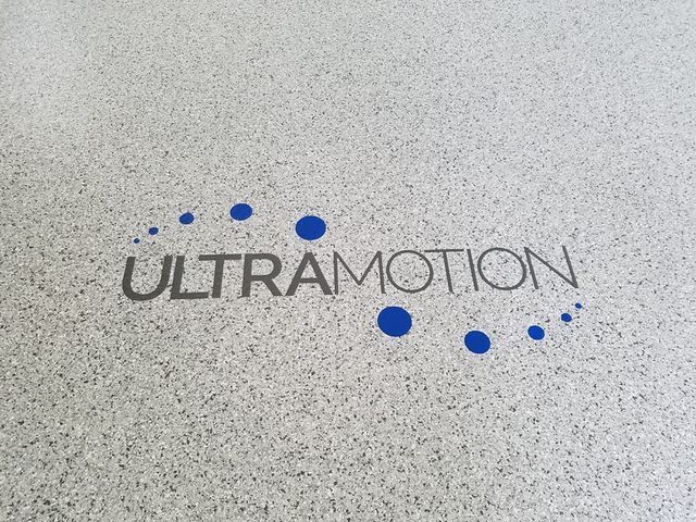 the word ultramotion is on a white surface with blue dots .