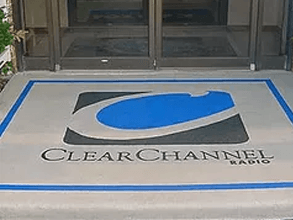 a clear channel radio logo is painted on the floor in front of a building .